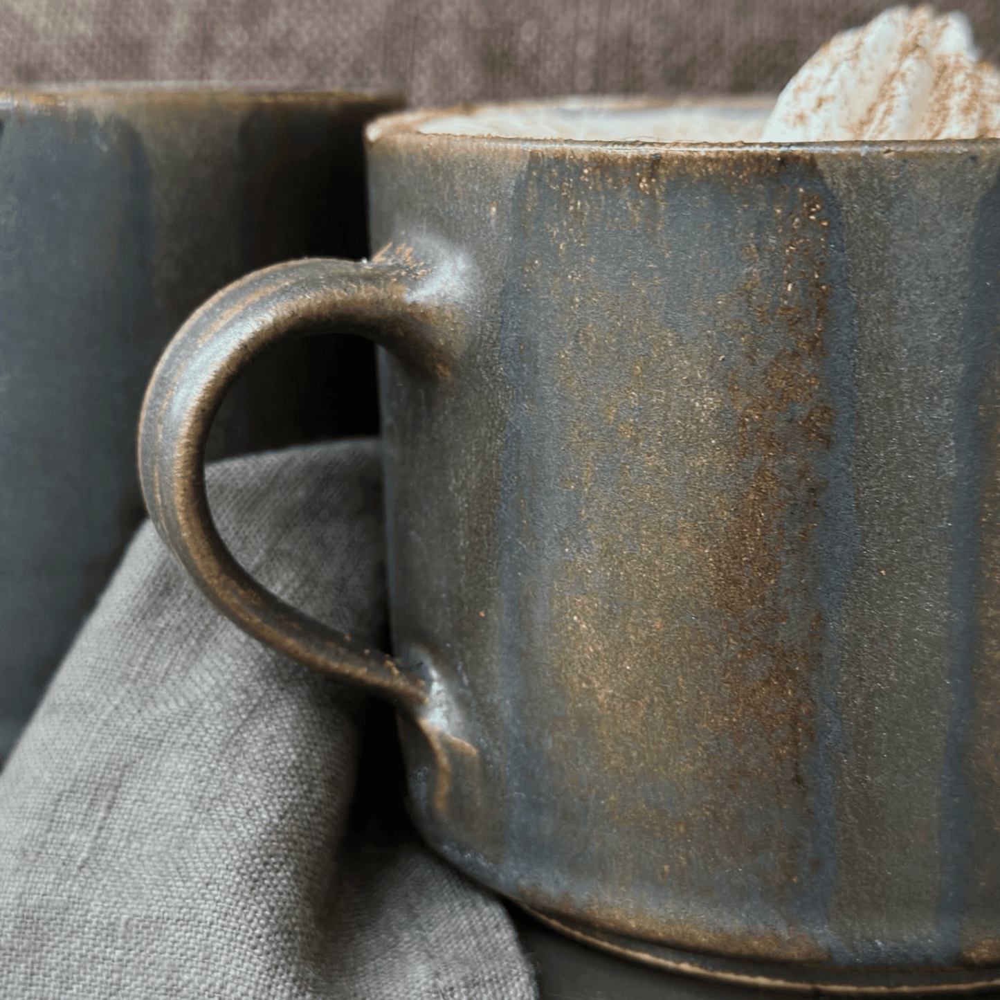 Handgjord brun tekopp i keramik med bredrandig glasyr i olika nyanser av brunt från serien Öland.