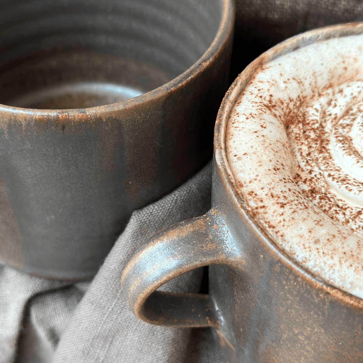 Handgjord brun tekopp i keramik med bredrandig glasyr i olika nyanser av brunt från serien Öland.