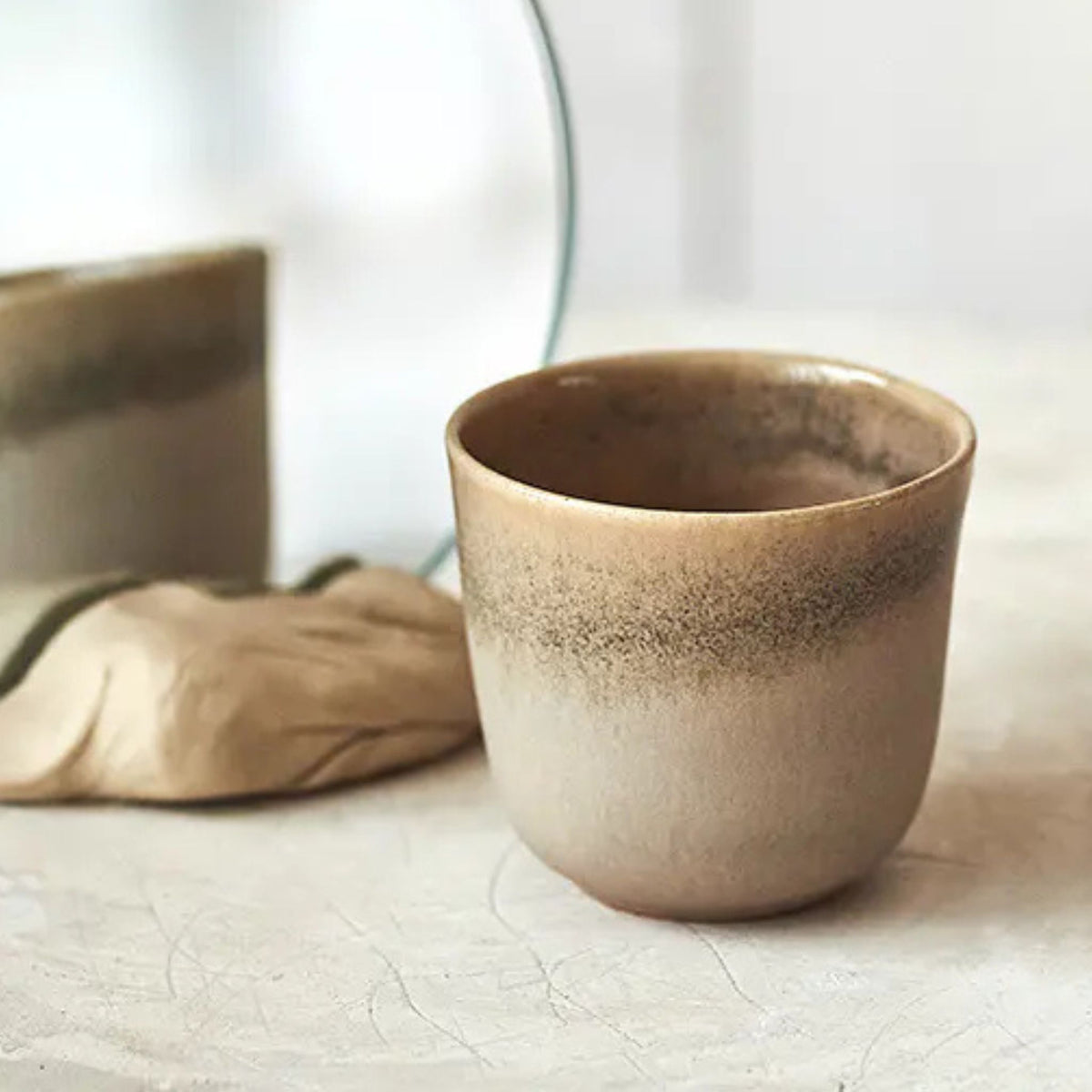 Handgjord keramikkopp från Paradisverkstaden i beige och bruna toner med mjukt skiftande glasyr.