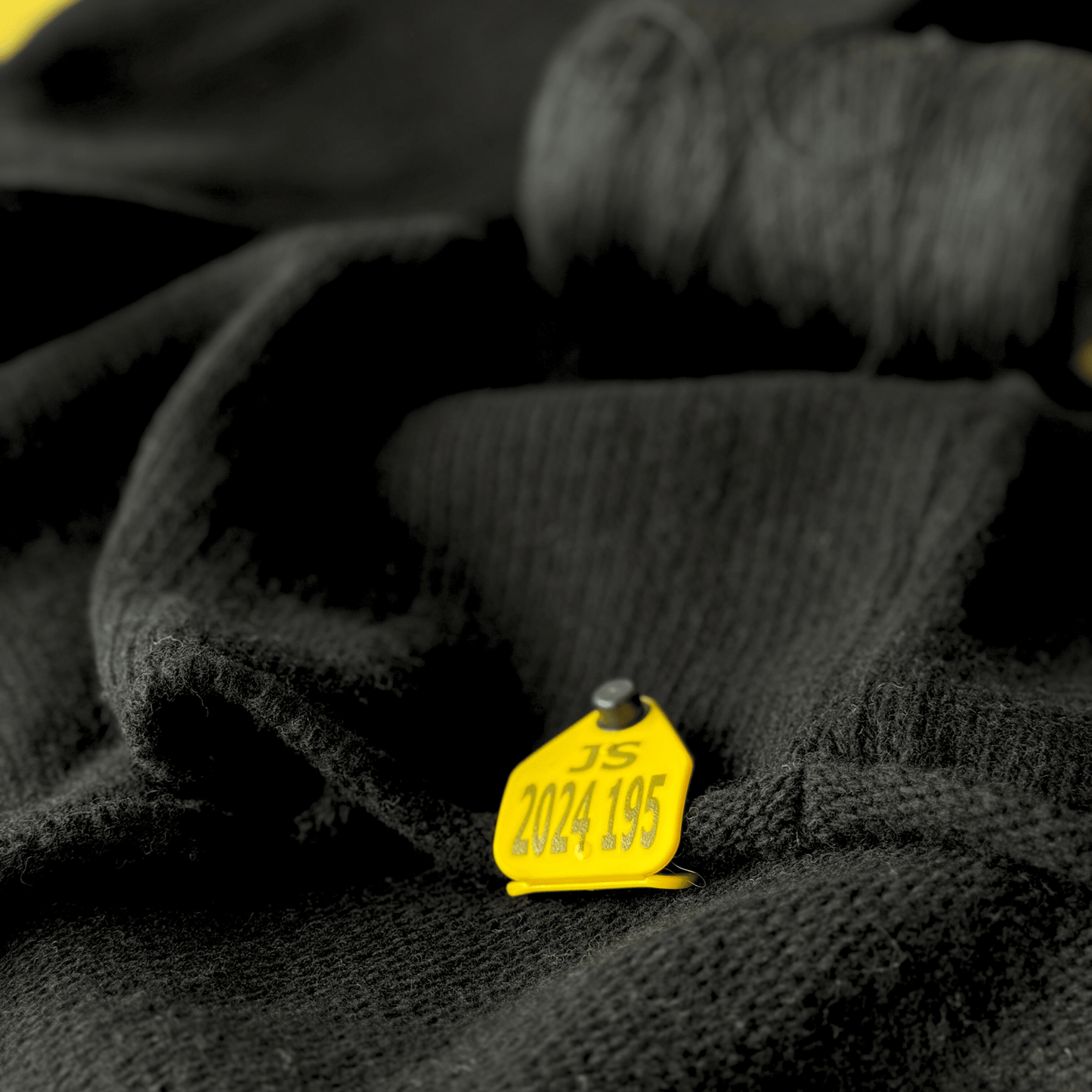 detalj med gul avsändare på svart stickad ulltröja av Alexander Stutterheim - John Sterner