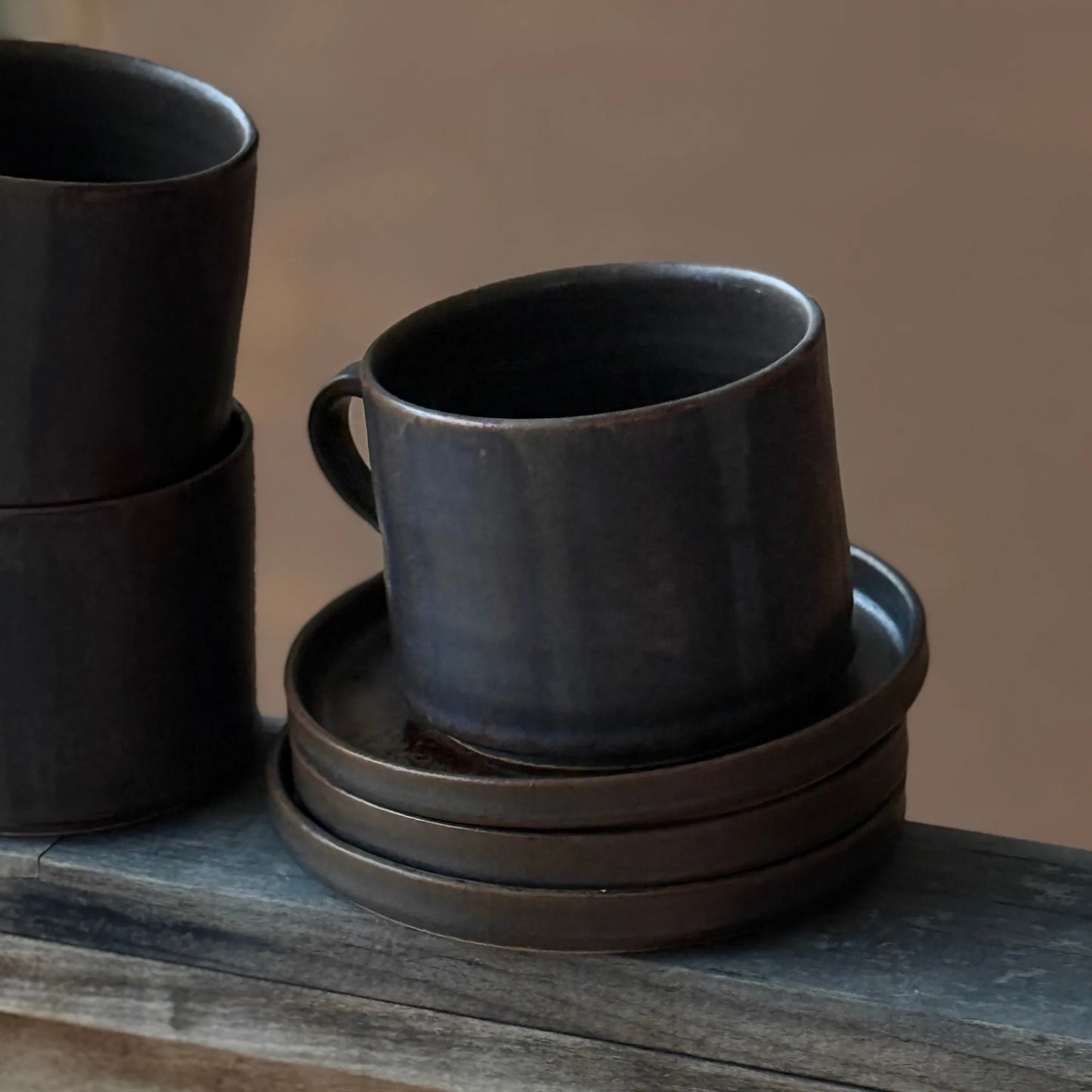 Handgjord brun tekopp i keramik med bredrandig glasyr i olika nyanser av brunt från serien Öland.